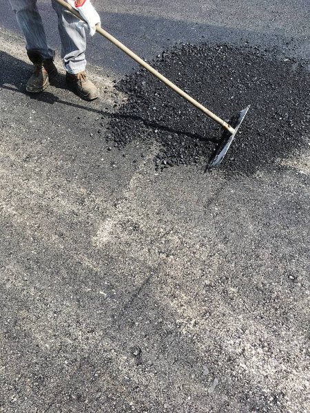 Worker asphalt a road in summer