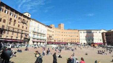Siena, İtalya - 02 Mart 2019: Piazza del Campo 'da turistler, Torre del Mangia' nın önünde dinlenin, meydan ünlü at yarışı Palio 'yu barındırdığı için tüm dünyada meşhurdur..