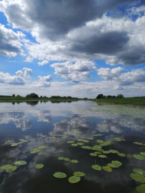 Fırtınadan önceki güzel gökyüzü. Bulutlar suya yansıyor. Yaz göleti.
