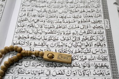 Kutsal Kur 'an, tespih ya da hasırın üzerindeki tasbih. Müslümanların kutsal kitabı Kur 'an, kahverengi dua paspasının üzerine konur. Kutsal El-Kur 'an ve Arapça yazı..