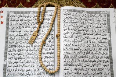 Müslümanların kutsal kitabı Kur 'an, kahverengi dua paspasının üzerine konur. Kutsal Kur 'an, tespih ya da hasırın üzerindeki tasbih. Kutsal El-Kur 'an ve Arapça yazı..