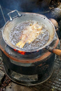 Kızgın yağlı eski çelik tavada kızarmış tilapia balığını kapat.