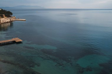 Türkiye 'de dar bir caddenin kenarında şeffaf bir deniz kıyısındaki ahşap iskele