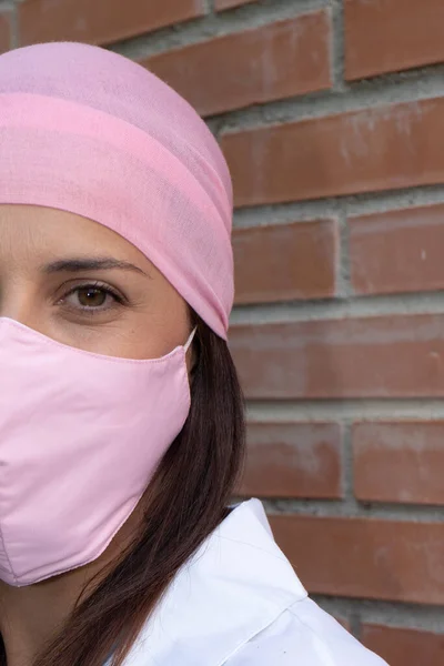 Beautiful Woman looking to the camera wearing pink scarf and pink mask from breast cancer. Lifestyle. Health