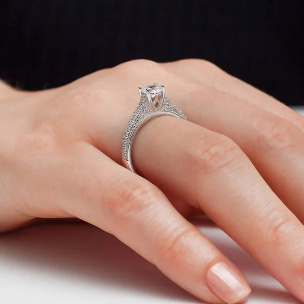 stringing jewelry on female finger polished hand on white background