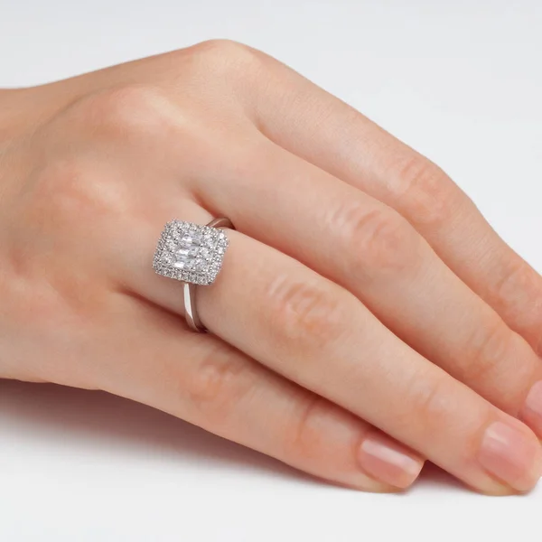 stringing jewelry on female finger polished hand on white background