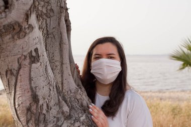 Bayan Covid-19 'dan korunmak için açık havada bir maske tarafından korunuyor. Doğal kaynaklar, ağaçlar ve temiz hava..