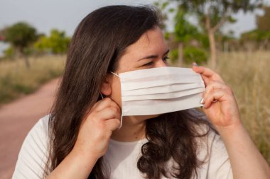 Bayan Covid-19 'dan korunmak için açık havada bir maske tarafından korunuyor. Doğal kaynaklar, ağaçlar ve temiz hava..