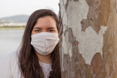 Bayan Covid-19 'dan korunmak için açık havada bir maske tarafından korunuyor. Doğal kaynaklar, ağaçlar ve temiz hava..