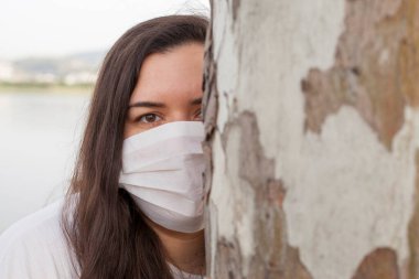 Bayan Covid-19 'dan korunmak için açık havada bir maske tarafından korunuyor. Doğal kaynaklar, ağaçlar ve temiz hava..