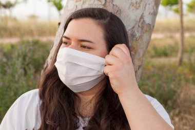 Bayan Covid-19 'dan korunmak için açık havada bir maske tarafından korunuyor. Doğal kaynaklar, ağaçlar ve temiz hava..