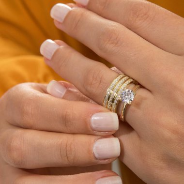 Gümüş, kadın modelinde desenli alyanslar, arkasında farklı renkler..