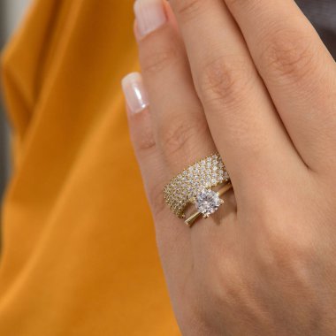 Gümüş, kadın modelinde desenli alyanslar, arkasında farklı renkler..