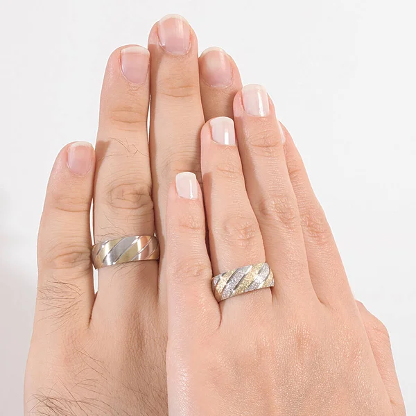 A pair of silver wedding rings worn on the finger of the male and female model.