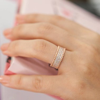 Gümüş, kadın modelinde desenli alyanslar, arkasında farklı renkler..