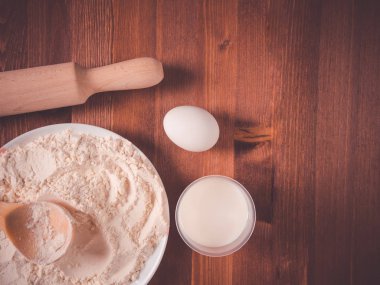 Bir kase, beyaz yumurta ve ahşap bir oklava ahşap arka plan üzerinde un. Üstten Görünüm