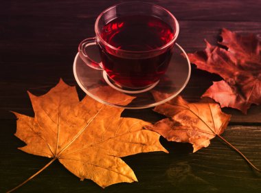 Fincan çay siyah ahşap zemin sonbahar yaprakları ile. Karanlık fotoğraf