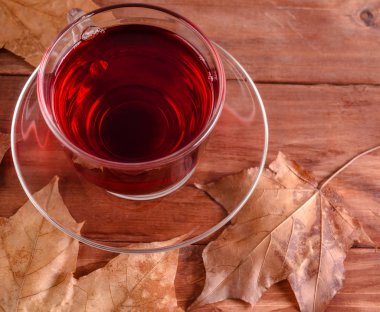 Bardak maple kırmızı çay ile ahşap bir masaya bırakır. Instagram