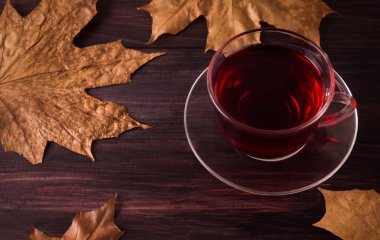 Ahşap bir masaya Kupası ile akçaağaç üzerinde kırmızı Çin çay yaprakları