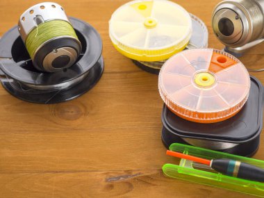 Üç balık tutma ele ve bir kayan nokta, turuncu yuvarlak yemler ve ahşap kurullarında yalan misina kutularını