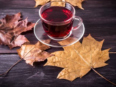 Fincan çay siyah ahşap zemin sonbahar yaprakları ile. Karanlık fotoğraf