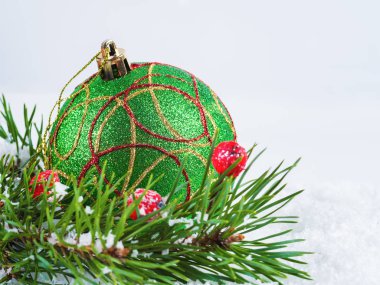 Yeşil Noel kar topu ve ladin dallarında