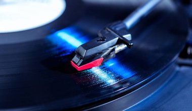 Vinil analog oynatıcının kalemi, dönen bir diskin yüzeyi ile temas eder.