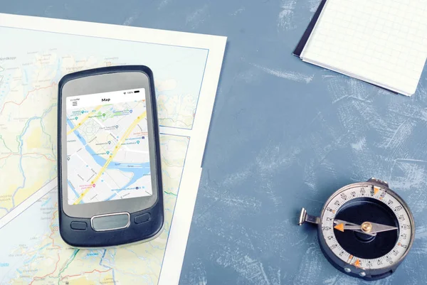 Smartphone auf Touristenkarte, Kompass und Notizblock — Stockfoto