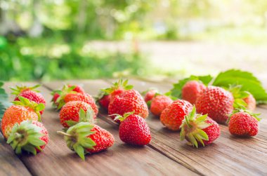 Olgun kırmızı çilek ahşap bir masa üzerinde.