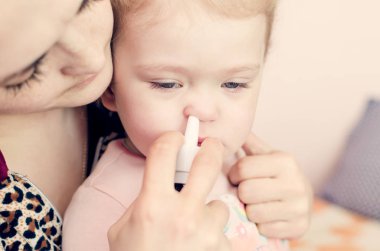 Anne küçük bir çocuğun burnuna damlıyor..