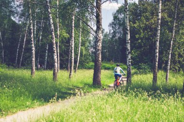 Bir kask bir bisikletçi ormanın içinden bir bisiklet yolu rides..