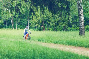 Bir kask bir bisikletçi ormanın içinden bir bisiklet yolu rides..