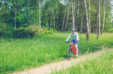 Bir kask bir bisikletçi ormanın içinden bir bisiklet yolu rides..