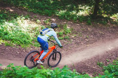 Bir kask bir bisikletçi bir turuncu bisiklet üzerinde dağdan iner.