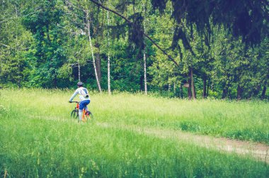 Bir kask bir bisikletçi ormanın içinden bir bisiklet yolu rides..