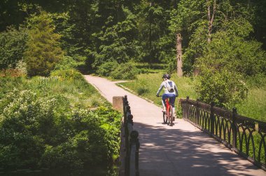 Parkta köprüde sürme kask bisikletçi.