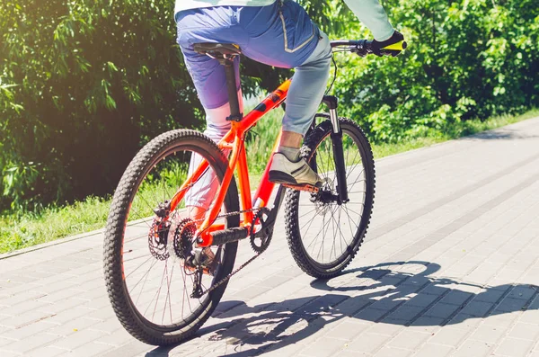 Cyclist on an orange bike riding a bicycle path.