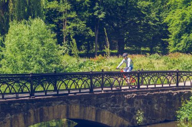 Parkta köprüde sürme kask bisikletçi.