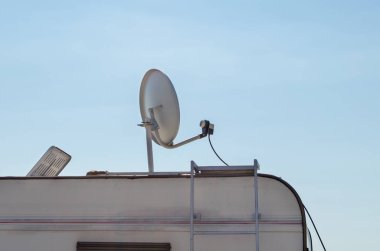 Mavi gökyüzü karşı bir karavan üzerinde beyaz uydu anteni.