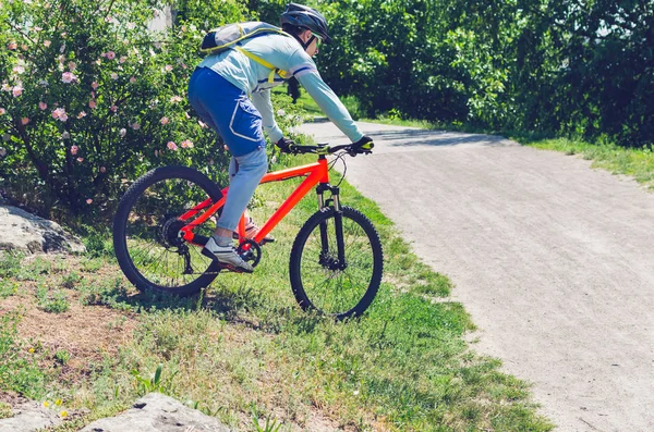 Cyclist on an orange bike riding a bicycle path.