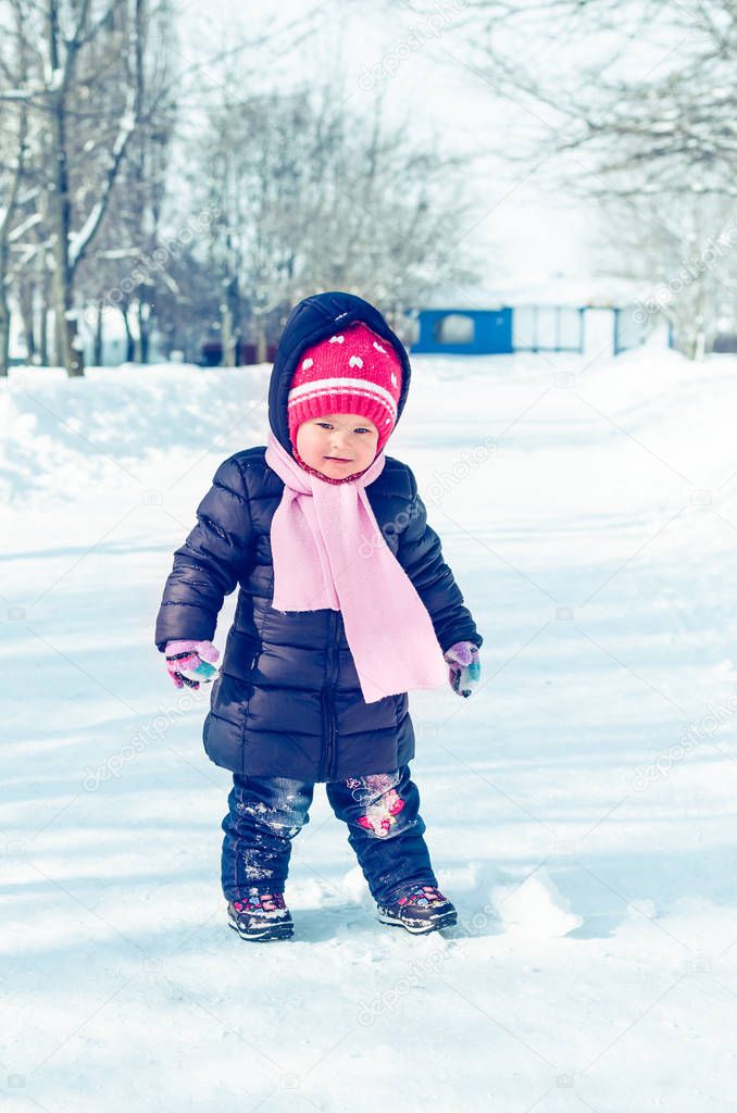 Little girl walks in winter on a snowy alley.