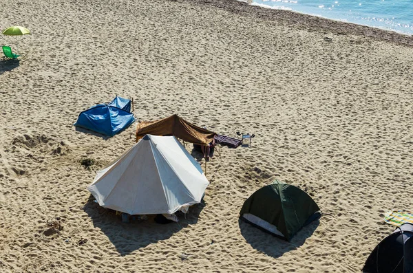 Tents and equipment for camping are on the sea beach.