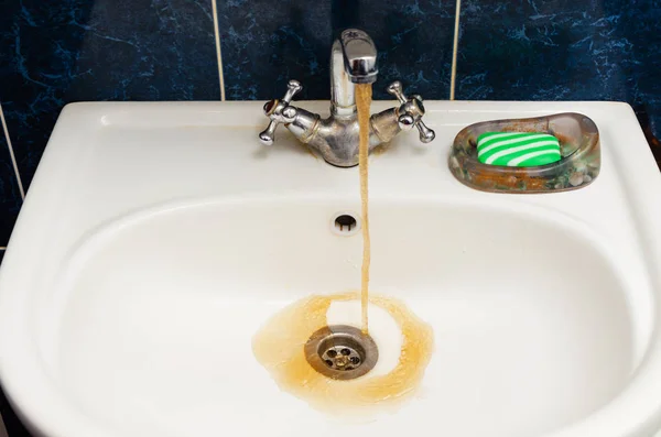 Beyaz bir lavabo kirli paslı su akar.