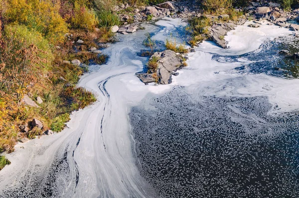 Polluted river, foam on the water surface top view.