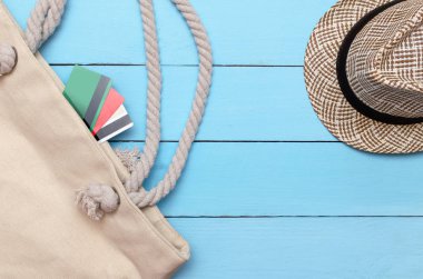 Ahşap bir masa üzerinde bir şapka yatıyor plaj çantası ve banka kartları