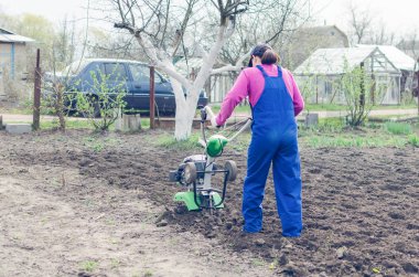 Genç kız bir bahar bahçesinde bir Kültüvatör ile çalışma.