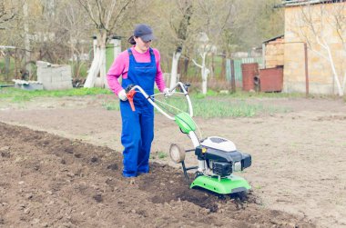 Genç kız bir bahar bahçesinde bir Kültüvatör ile çalışma.