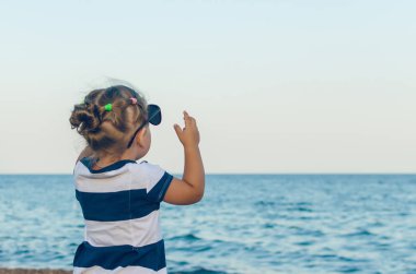 Güneş gözlüğü gösterir eliyle bir şey üzerinde küçük bir kız.