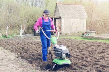 Genç kız bir bahar bahçesinde bir Kültüvatör ile çalışma.
