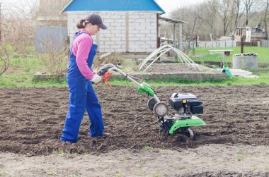 Genç kız bir bahar bahçesinde bir Kültüvatör ile çalışma.
